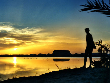 דמות אדם שחור מול אגם שהשקיעה משתקפת בו (צילום: אור גץ, SXC1)