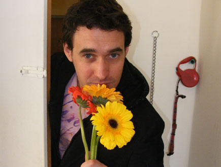 בחור מחזיק פרחים בפתח דלת (צילום: איתי בוטבגה)