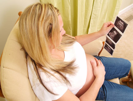 אשה בהריון מסתכלת על צילומי אולטרא סאונד (צילום: SchulteProductions, Istock)