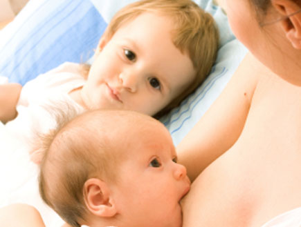 אם מניקה את תינוקה ואחיו מסתכל (צילום: istockphoto)