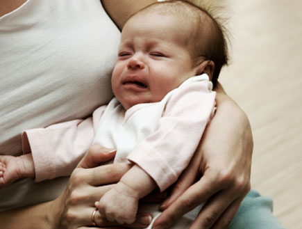 תינוק בוכה בידי אמו (צילום: Nikolay Suslov, Istock)