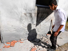 אדם עומד ליד קיר שהופצץ (צילום: רויטרס, חדשות)