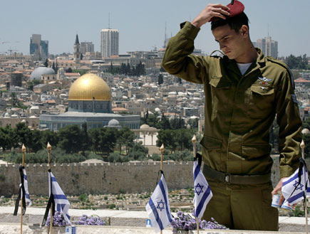 חייל מחזיק על ראשו כומתה של הצנחנים ומסתכל על דגלי ישראל (תמונת AVI: עדי רם, חדשות)