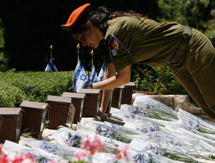 חיילת עם כומתה כתומה מניחה דגלים בגינה (תמונת AVI: עדי רם, חדשות)