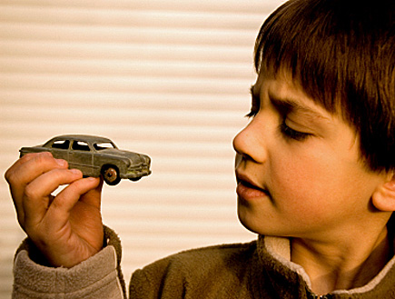 ילד בחולצה חומה מסתכל אל מכונית צעצוע (צילום: RMAX, Istock)