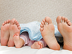 כפות רגליים של הורים ובינהם כפות רגליים של תינוק ע