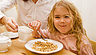 ילדה בלונדינית אוכלת קורנפלקס ליד אמה (צילום: alkir, Istock)