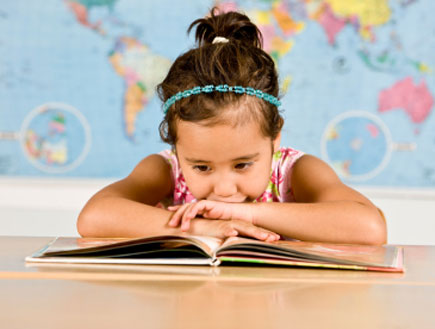 ילדה עם קשת תכולה בשיערה נשענת קדימה וקוראת בספר (צילום: btrenkel, Istock)