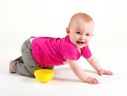 תינוקת בחולצה ורודה זוחלת על הברכיים כשלידה קערית (צילום: istockphoto)