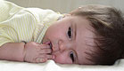 תינוק שוכב כשאצבעותיו בפיו (צילום: Jessica Asmar, Istock)