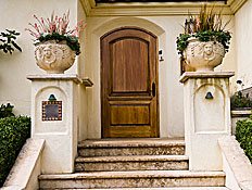 כניסה מרשימה לבית, עם דלת מעץ ועציצים