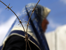 אשה פלסטינית מבעד לגדר תייל (צילום: רויטרס)
