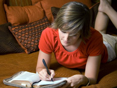 בחורה כותבת מכתב על ספה (צילום: Loretta Hostettler, Istock)