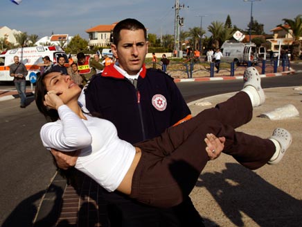 חובש ישראלי מפנה פצועה מזירת נחיתת רקטה באשקלון (צילום: רויטרס)