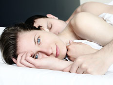 גבר ישן ואישה מחייכת במיטה (צילום: TommL, Istock)