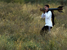 נער ישראלי סוחב שיירי קסאם שנחת בניר עם (רויטרס) (צילום: רויטרס)