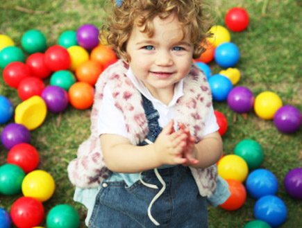 ילדה בהירת עיניים משחקת בכדורים צבעוניים בגן (צילום: Anne Clark, Istock)