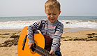 ילד מנגן בגיטרה בים (צילום: stask, Istock)