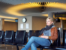 אשה יושבת על ספסל בשדה תעופה (צילום: Urs Kuester, GettyImages IL)