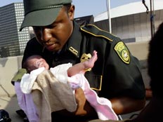 שוטר מחזיק תינוק (צילום: רויטרס)