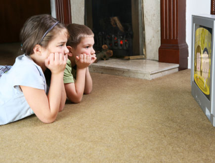 ילדים שוכבים על השטיח וצופים בטלויזיה