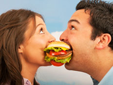 אישה וגבר נוגסים בהמבורגר (צילום: 101cats, Istock)