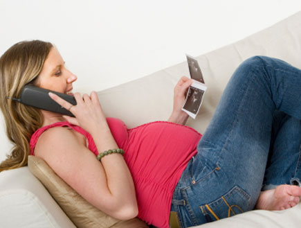 אישה בהריון בטלפון מסתכלת על תמונה (צילום: digitalskillet, Istock)