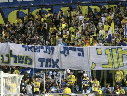 האוהדים הצהובים מחזיקים שלטים למוני (אור שפונדר) (צילום: מערכת ONE)