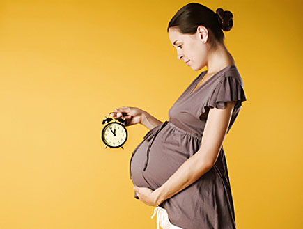 אישה בהריון מחזיקה שעון מעורר (צילום: istockphoto)