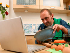 גבר מבשל מול לפטופ (צילום: Brasil2, Istock)