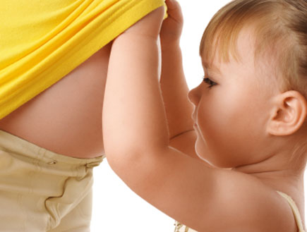 ילדה מסתכלת על הבטן של אמא בהריון (צילום: Kobyakov, Istock)
