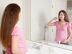 אישה בהריון מצחצחת שיניים (צילום: Sharon Dominick, Istock)