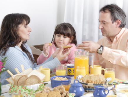 הורים וילדה יושבים בשולחן ואוכלים (צילום: Grafissimo, Istock)