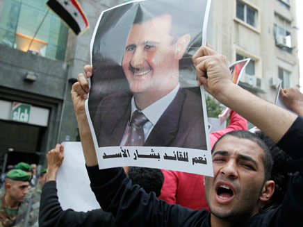 מפגין עם תמונה של שליט סוריה בשאר אסד (צילום: רויטרס)