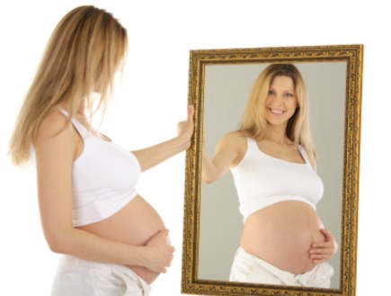 אישה בהריון מסתכלת על עצמה במראה (צילום: istockphoto)