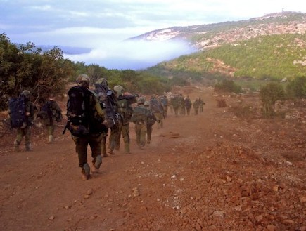 פזם חיילים הולכים בשטח ברקע עננים על הר (צילום: לירון אראל)