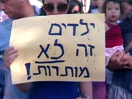 אם מחזיקה שלט מחאה, בהפגנה בת