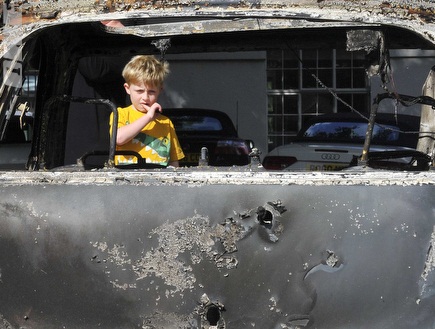 ילד מסתכל על המכונית השרופה (רויטרס) (צילום: מערכת ONE)