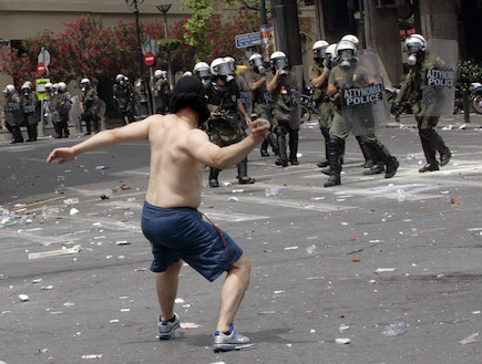 מפגין מיידה אבנים על שוטרים ביוון (צילום: Milos Bicanski, GettyImages IL)