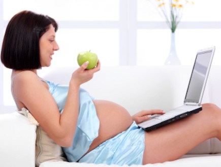 אישה בהריון מול מחשב אוכלת תפוח (צילום: kristian sekulic, Istock)