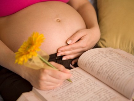 אישה בהריון מחזיקה עט וכותבת ביומן (צילום: Derek Latta, Istock)