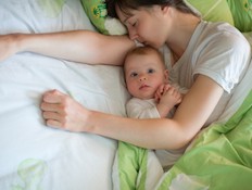תינוק ער ואמא ישנה לידו במיטה (צילום: zergkind, Istock)