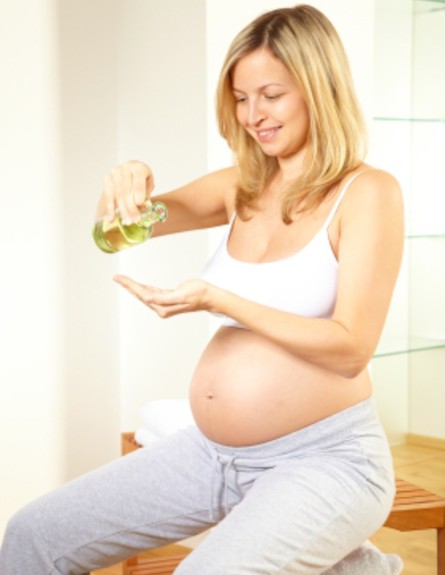 אישה בהריון מורחת שמן על בטנה (צילום: Hannes Eichinger, Istock)