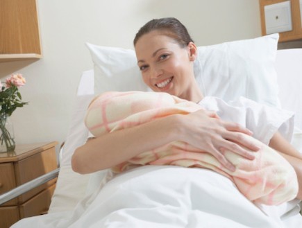 אישה אחרי לידה מחבקת תינוק עטוף בשמיכה (צילום: אימג'בנק / Thinkstock)