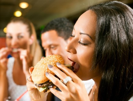 אישה אוכלת המבורגר במסעדה (צילום: אימג'בנק / Thinkstock)