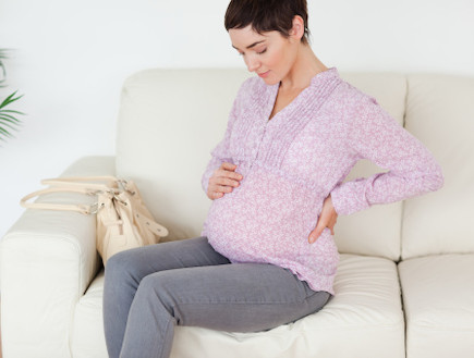 אישה בהריון יושבת על הספה (צילום: אימג'בנק / Thinkstock)