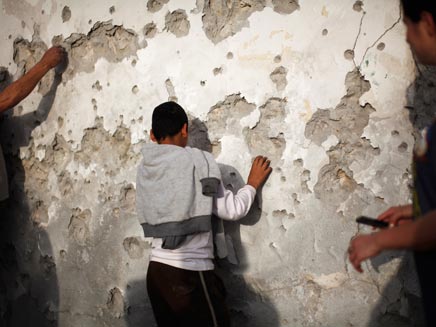 ילד מול קיר שנפגע מרסיסים בבאר שבע