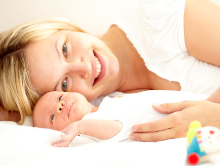 תינוק שוכב לצד אמא מחייכת (צילום: אימג'בנק / Thinkstock)