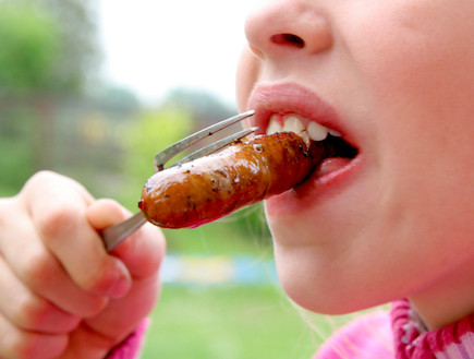 ילדה אוכלת נקניקייה (צילום: istockphoto)