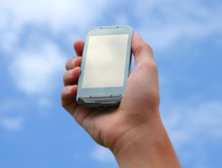 יד מחזיקה טלפון סלולרי על רקע שמיים  (צילום: אימג'בנק / Thinkstock)
